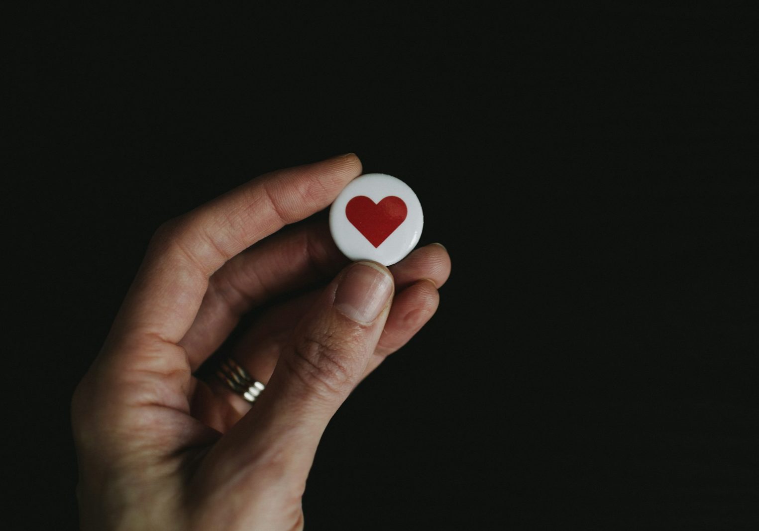 person holding red and white hear button